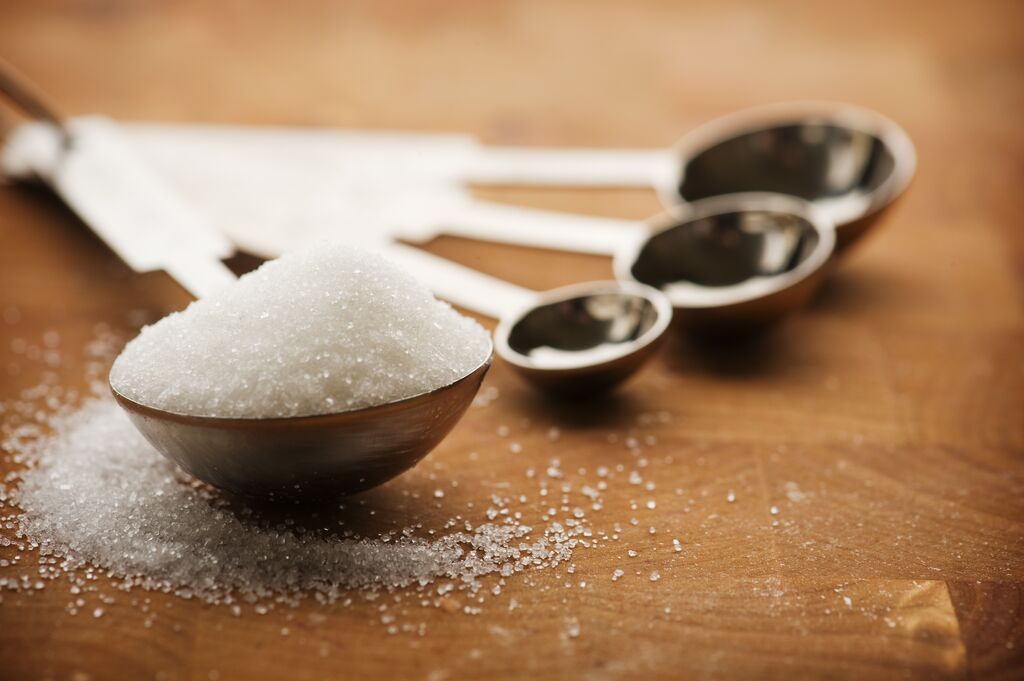 Measuring spoon filled with granulated sugar.