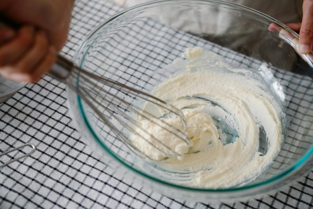 person stirring whipping cream in a bowl