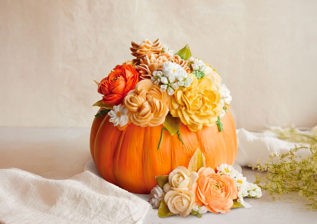 Pumpkin cake decorated with orange, peach, and white buttercream flowers