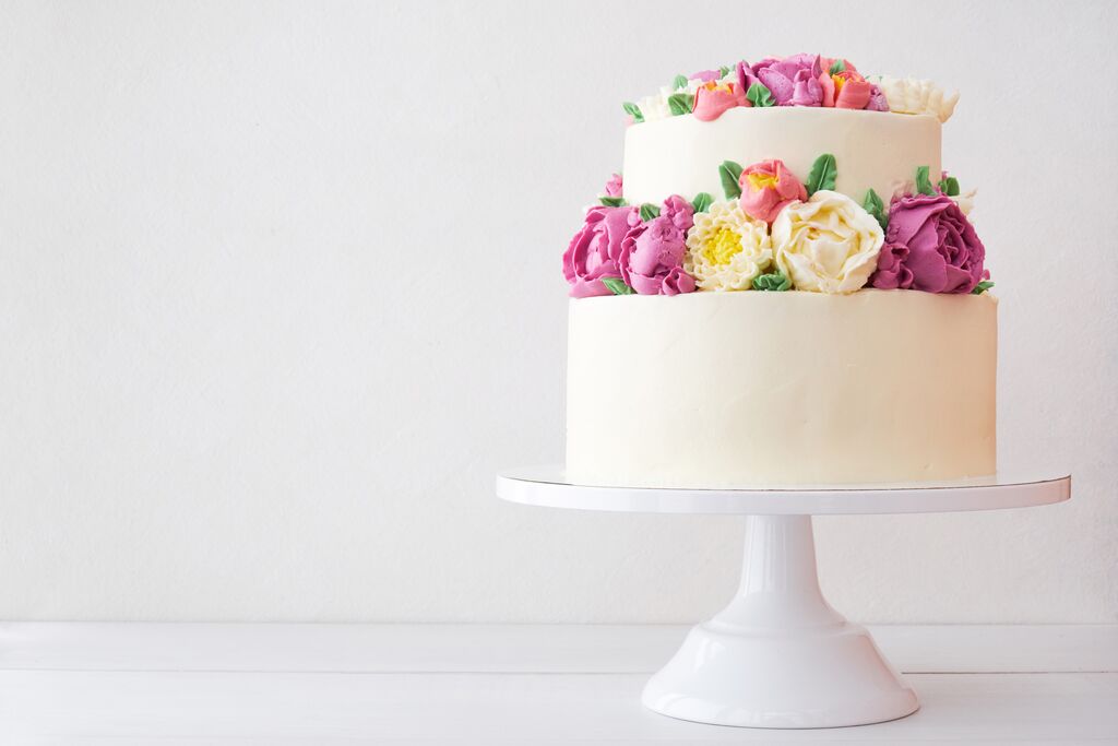 Elegant white floral cake decorated with pink and yellow buttercream flowers