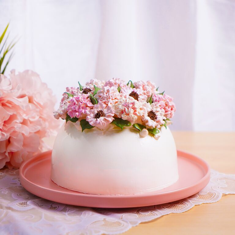 Pink frosted cake topped with fresh pink floral decorations