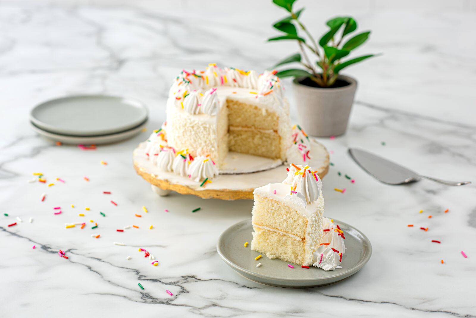 Vanilla cake with whipped cream and colourful sprinkles.