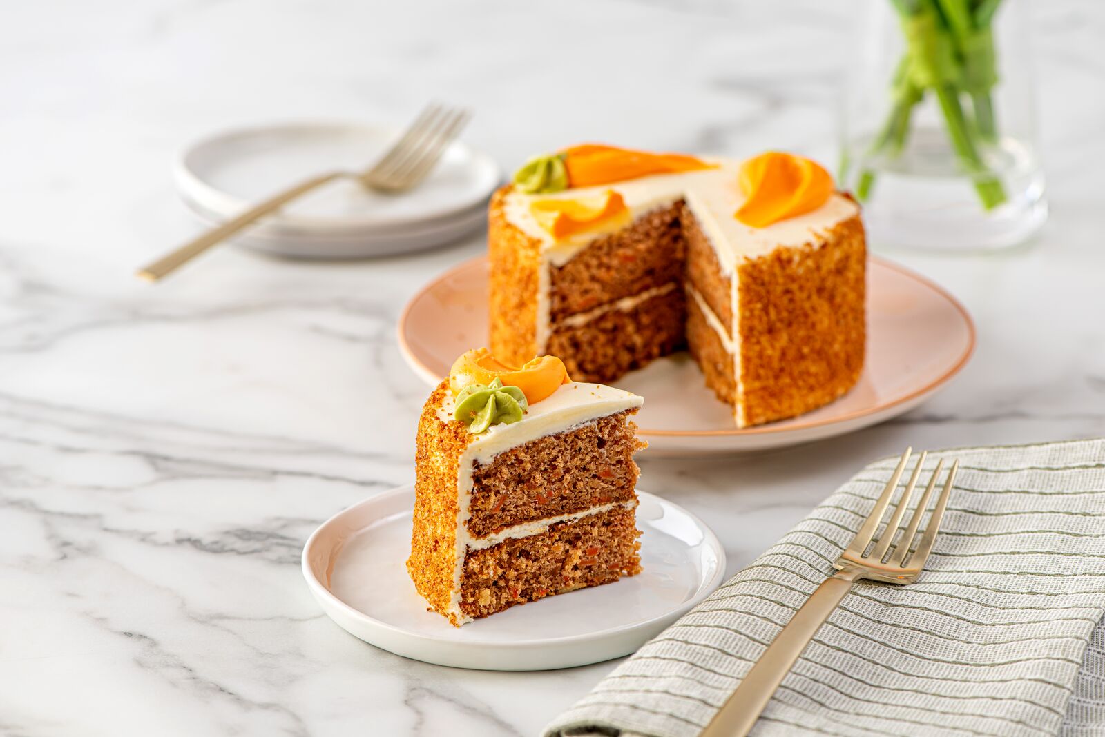 Carrot cake with cream cheese frosting and orange garnish.
