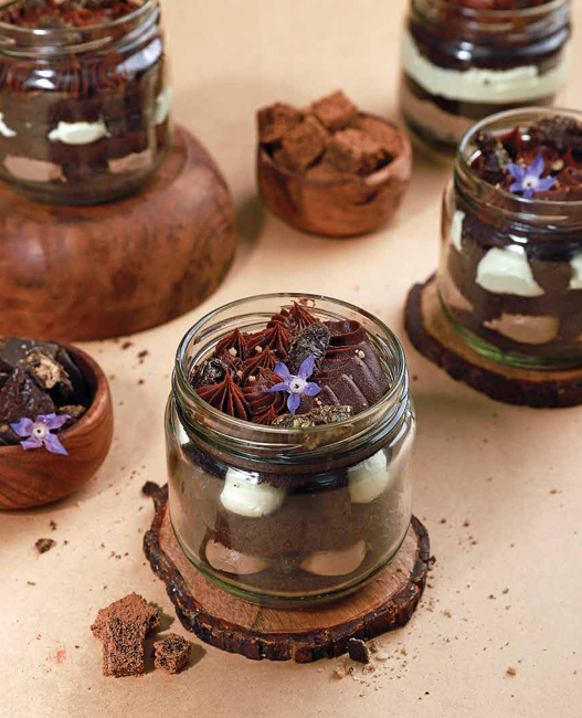Chocolate dessert jars with star anise and edible flowers.