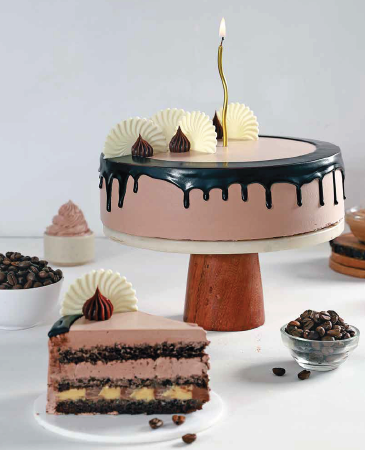 Chocolate layer cake with pink frosting and dark chocolate glaze