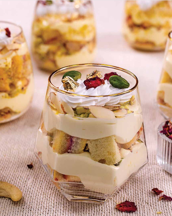 Dry fruit trifle with cream, cake layers, nuts and rose petals.