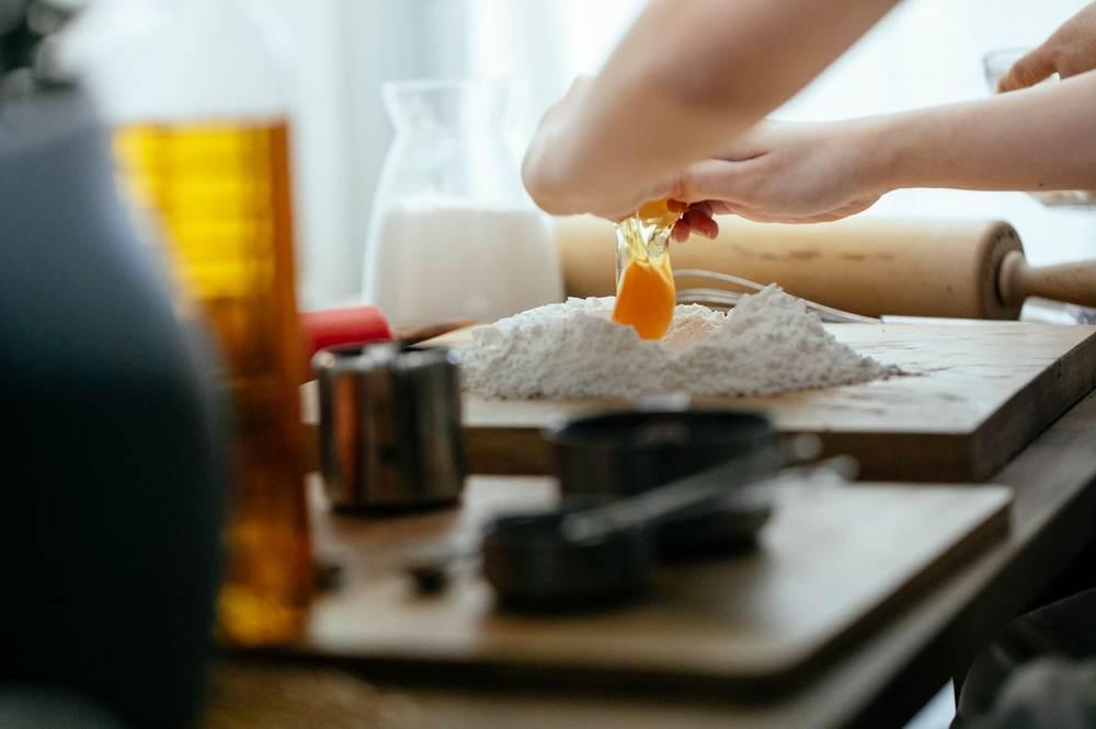 Cracking an egg into a mound of flour surrounded by milk and other baking ingredients