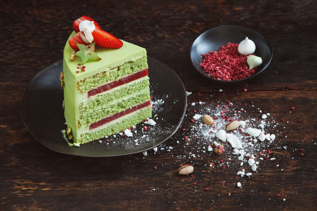 Green pistachio cake with raspberry filling and fresh strawberries.