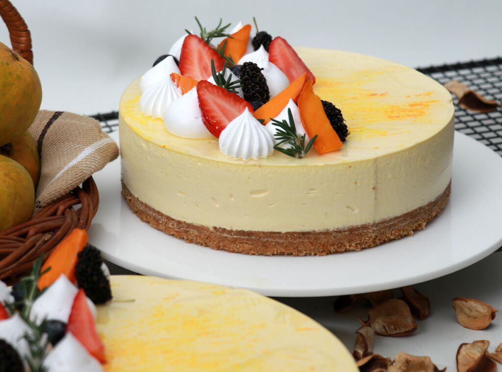Mango cheesecake topped with fresh strawberries and fruit.