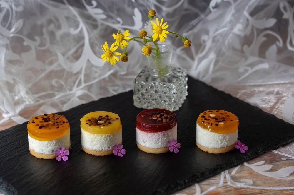 Assorted mini no-bake cheesecakes with fruit toppings on a slate board