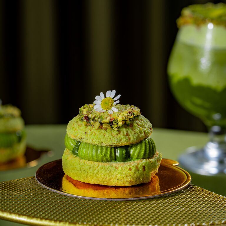 Green pistachio dessert topped with crushed pistachios and a flower.