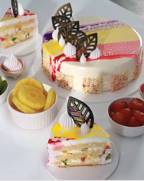 Colourful triple treat cake with cream, fruit layers and chocolate decorations.