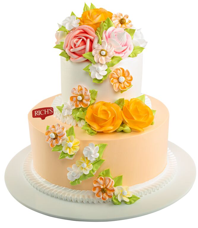 White two-tier buttercream cake decorated with pink and cream piped flowers