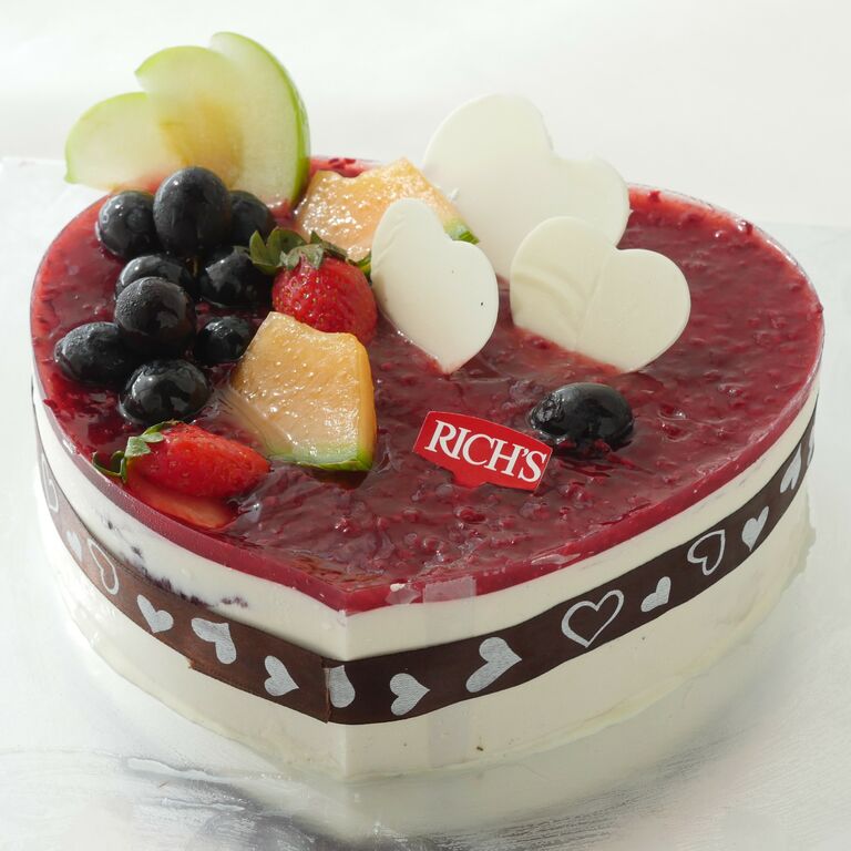Heart-shaped celebration cake with a cream filling and fresh berry topping