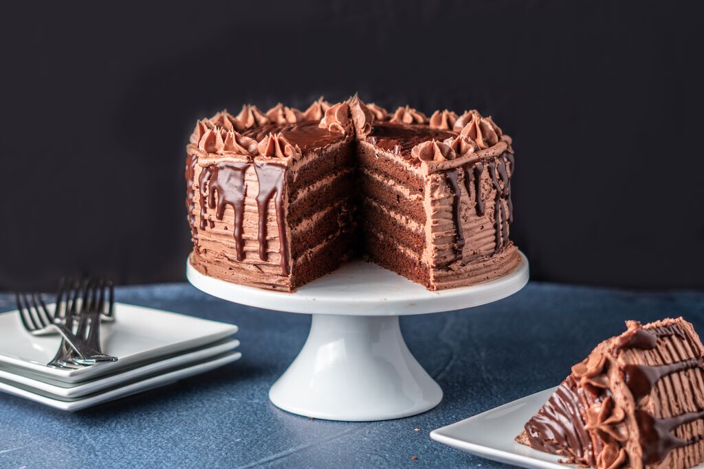 Chocolate truffle cake cut open to show ganache layers, with piped rosettes and drips