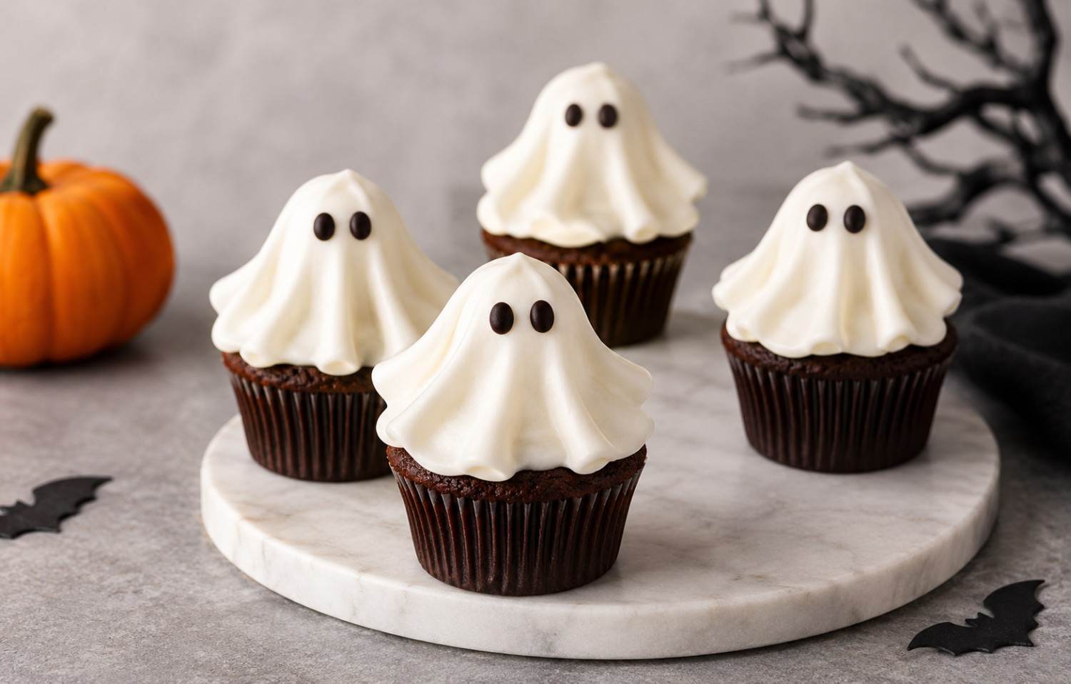 Chocolate cupcakes topped with white whipped cream ghosts with chocolate eyes