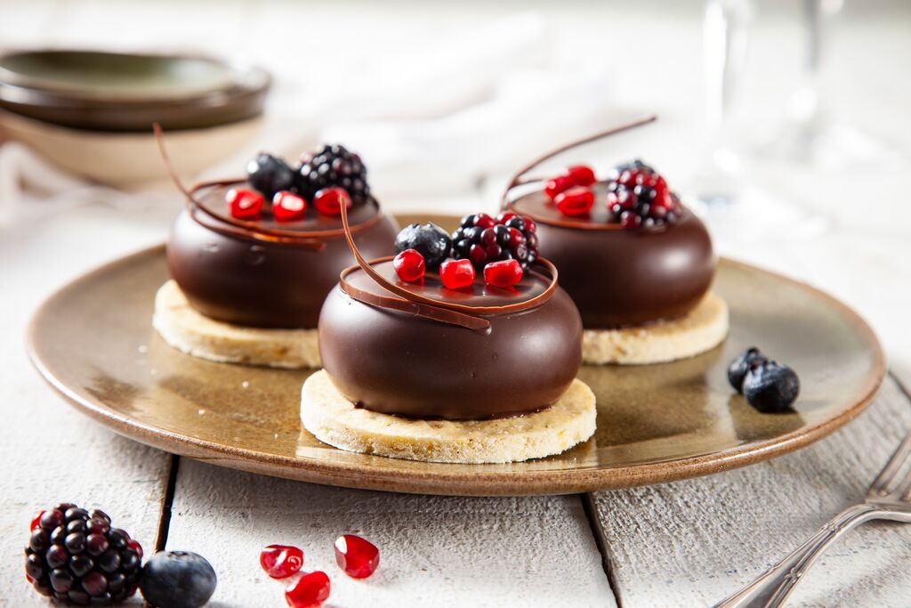 Chocolate dome desserts with a glossy ganache glaze and fresh berries