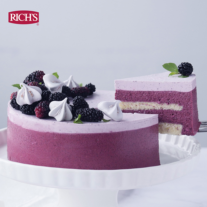 Cross-section of a berry mousse cake showing cream and fruit cake fillings between sponge layers