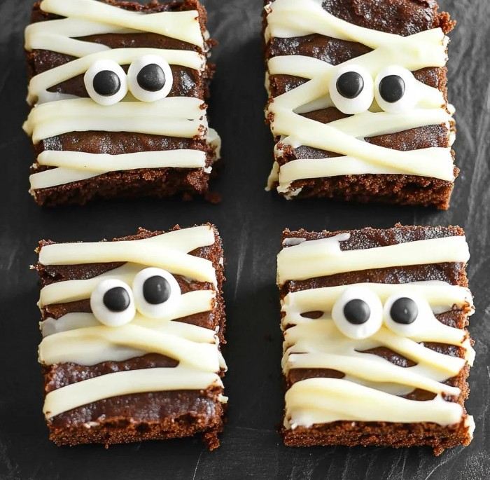 Halloween mummy brownies with white piped bandages and candy eyes
