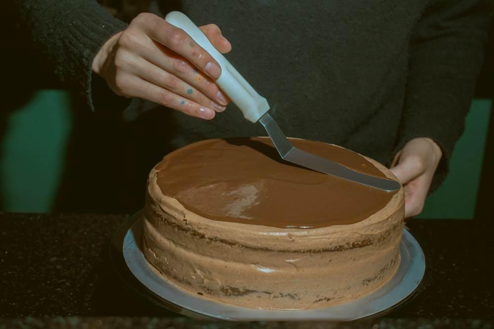 Smoothing a chocolate frosting top with an offset spatula for a clean finish