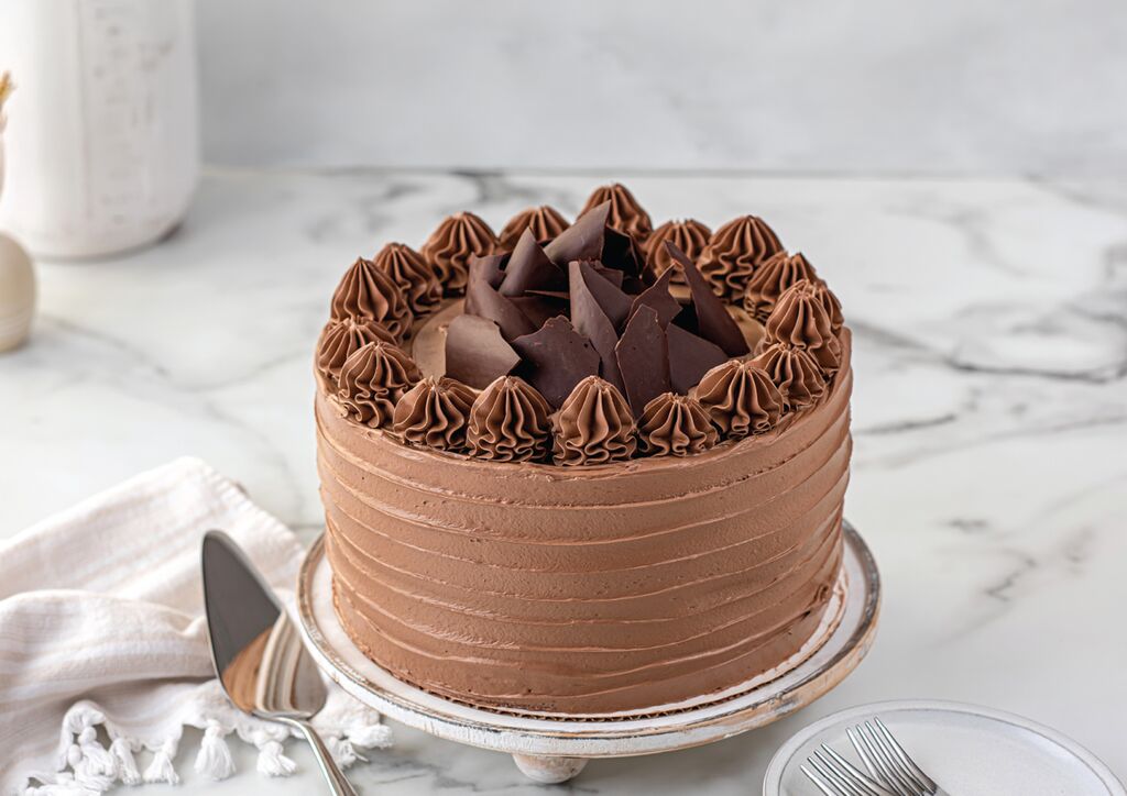 Chocolate cake with textured ridged sides and piped chocolate rosettes