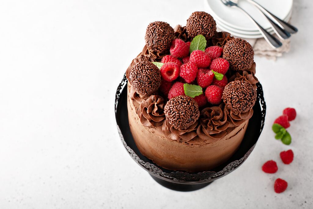 Chocolate truffle ganache cake topped with chocolate truffles and fresh raspberries