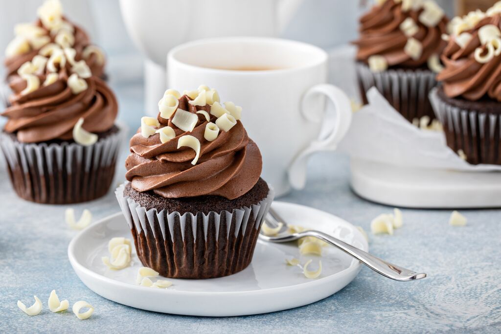 Chocolate cupcakes topped with piped whipped ganache and white chocolate curls