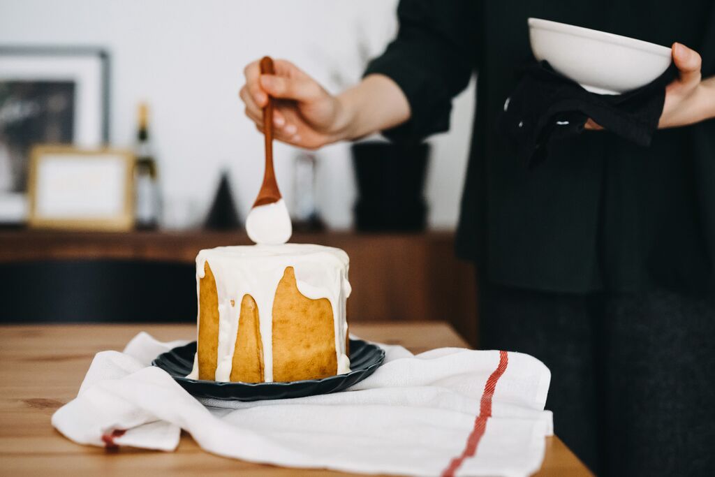 White chocolate ganache drip being poured over a small cake