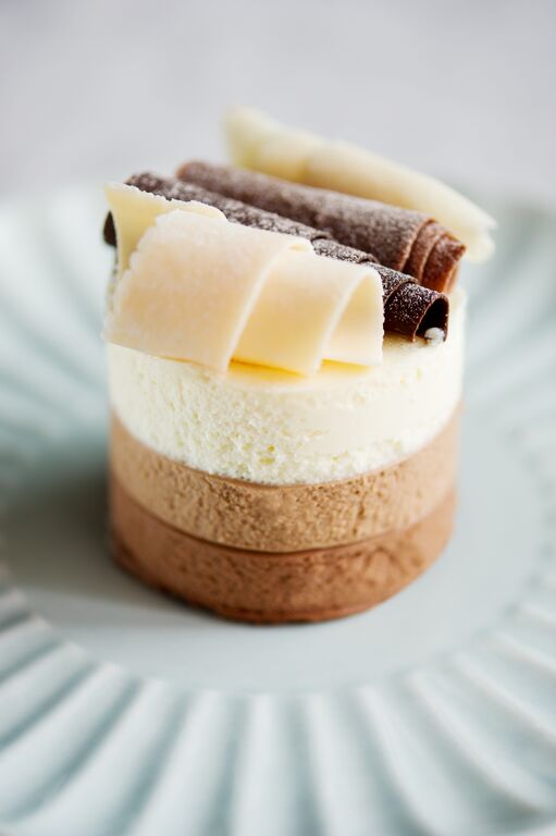 Mini layered mousse dessert with white and milk chocolate ganache and chocolate curls
